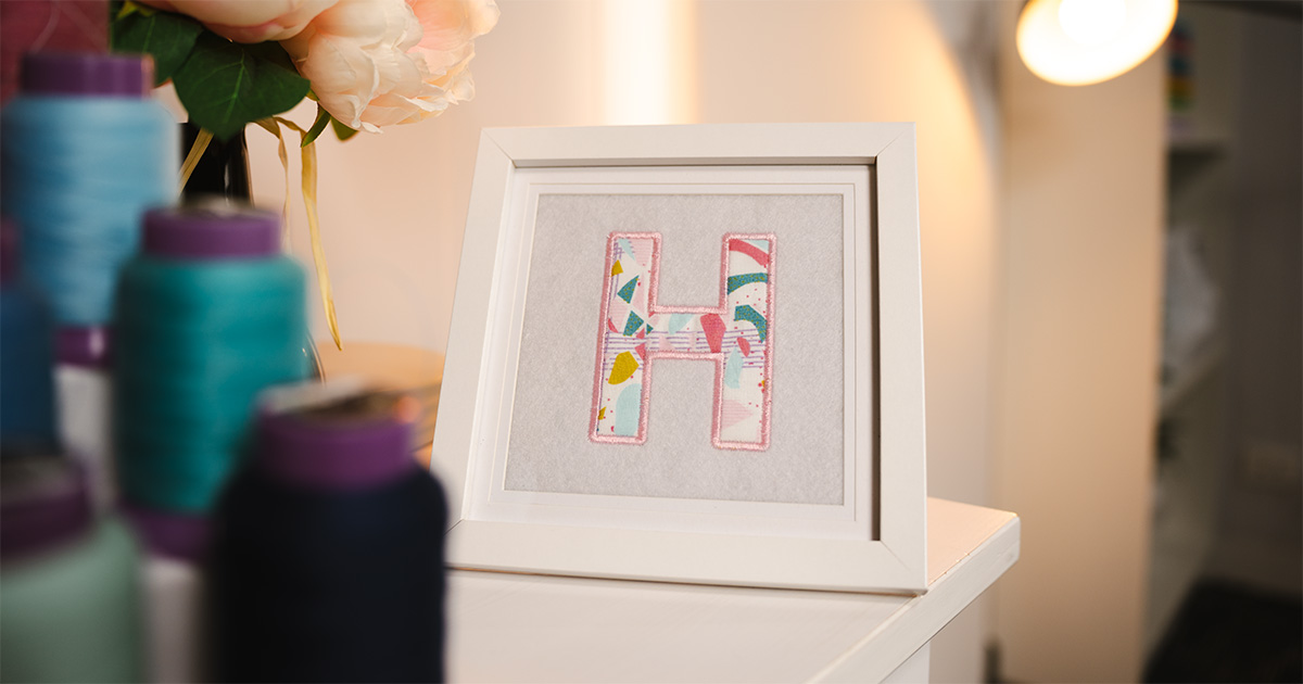 Finished framed applique letter artwork displayed on a shelf