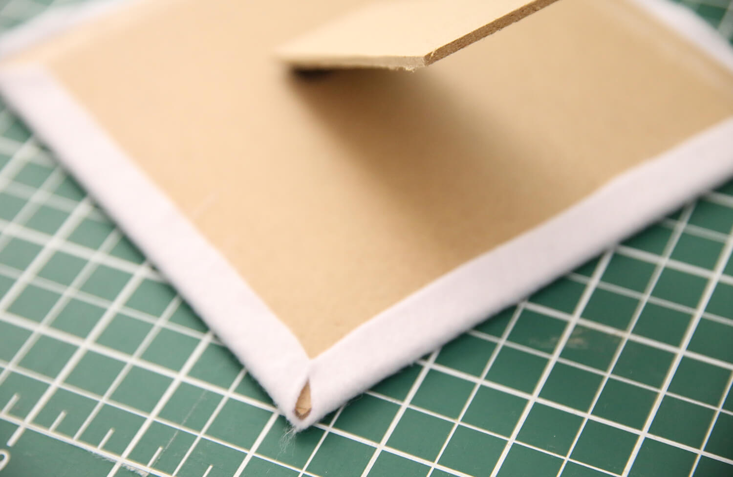 Folding felt edges neatly over the taped frame backing board