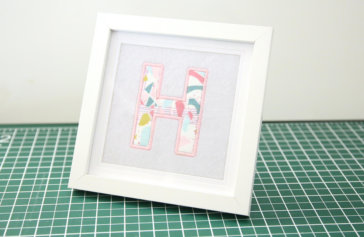 Finished framed applique letter artwork displayed on a shelf